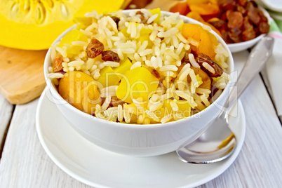 Pilaf fruit with pumpkin in bowl and spoon on board