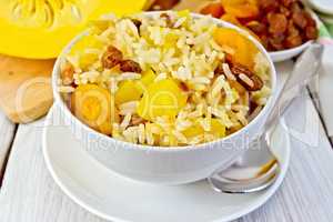 Pilaf fruit with pumpkin in bowl and spoon on board