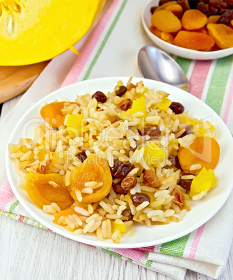 Pilaf fruit with pumpkin in white plate on light board