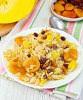 Pilaf fruit with pumpkin in white plate on light board