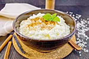 Rice porridge with cinnamon in bowl on board