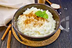 Rice porridge with cinnamon in bowl on dark board
