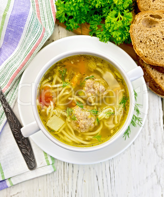 Soup with meatballs and noodles in bowl on board top