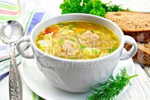 Soup with meatballs and noodles in bowl on saucer