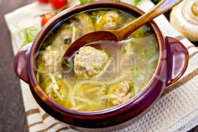 Soup with meatballs and noodles in pottery on napkin