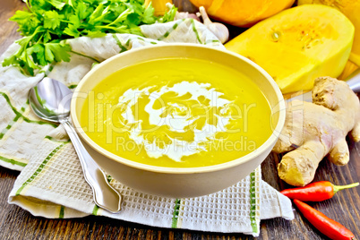 Soup-puree pumpkin with cream in bowl on napkin and board