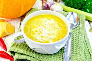 Soup-puree pumpkin with cream in white bowl on green napkin