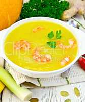 Soup-puree pumpkin with shrimp in white bowl on light board