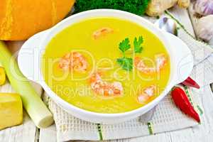 Soup-puree pumpkin with shrimp in white bowl on napkin