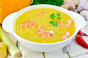 Soup-puree pumpkin with shrimp in white bowl on table