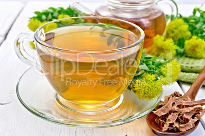 Tea of Rhodiola rosea in cup with spoon on board
