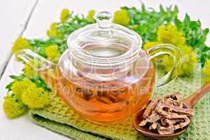 Tea of Rhodiola rosea in glass teapot with spoon on board