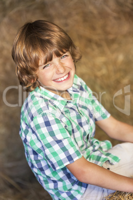 Happy Boy Child Sitting Smiling on Hay Bales