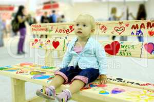 little fashionable baby sits on the painted bench