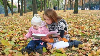 little sisters read the book in the autumn park