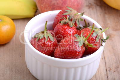 Bananas apple mandarin peach strawberry on wooden background as health food concept