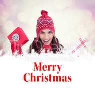 Composite image of festive brunette in winter clothes holding gi