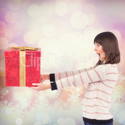 Composite image of surprised brunette holding a gift