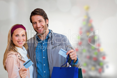 Composite image of smiling couple with shopping bags showing cre