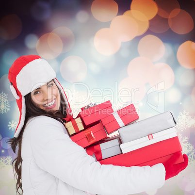 Composite image of festive brunette in winter clothes holding ma