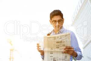 Businessman drinking coffee reading newspaper
