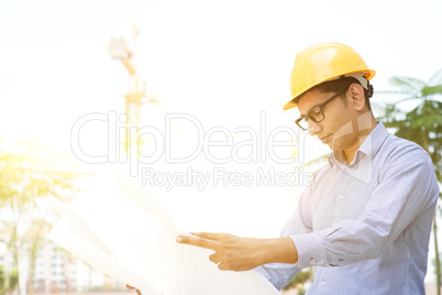 Asian Indian male contractor engineer reading blueprint