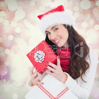 Composite image of smiling brunette holding christmas gifts