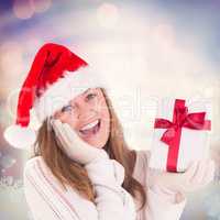 Composite image of festive blonde holding a gift