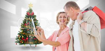 Composite image of couple with shopping bags and tablet