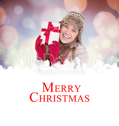 Composite image of happy blonde in winter clothes holding gift