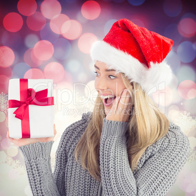 Composite image of festive blonde holding christmas gift