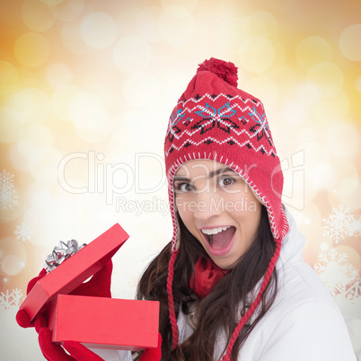 Composite image of excited brunette opening a christmas gift