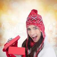Composite image of excited brunette opening a christmas gift