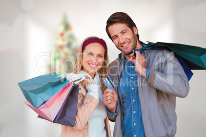 Composite image of smiling couple with shopping bags in front of