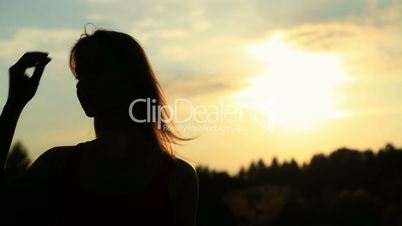 A silhouette of a woman  on a sunset touching her hair