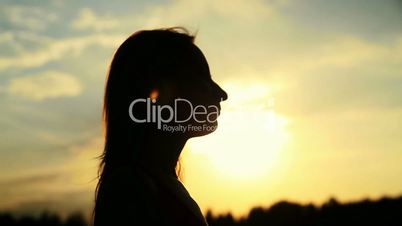 A silhouette of a woman  on a sunset touching her hair