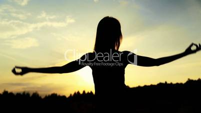 Silhouette of the woman dancing during beautiful sunset. Natural light and darkness.