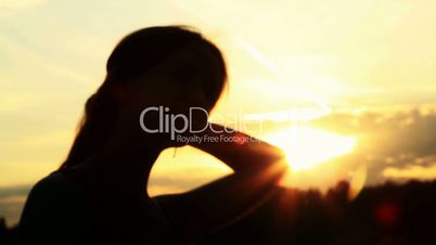 A silhouette of a woman  on a sunset touching her hair