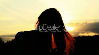 A silhouette of a woman  on a sunset comb her hair