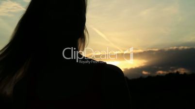 A silhouette of a woman  on a sunset comb her hair