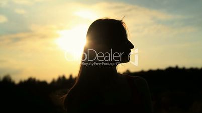 A silhouette of a woman  on a sunset touching her hair