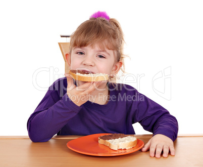 hungry little girl eats bread with chocolate cream