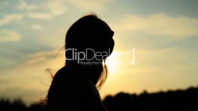 A silhouette of a woman  on a sunset touching her hair