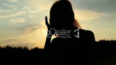 A silhouette of a woman  on a sunset touching her hair