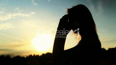 A silhouette of a woman  on a sunset touching her hair