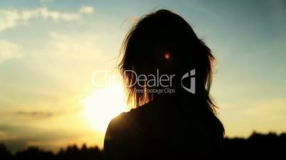 A silhouette of a woman  on a sunset turns her head