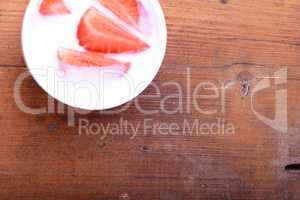 Slice of pie with strawberry on white plate, milk drink, wooden background. Top view