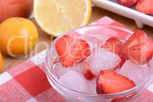 A slice of red strawberry on glass plate with lemon and mandarin in party theme background