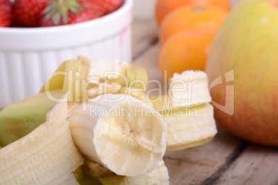 Bananas apple mandarin peach strawberry on wooden background as health food concept