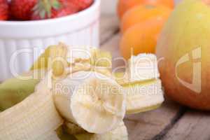 Bananas apple mandarin peach strawberry on wooden background as health food concept